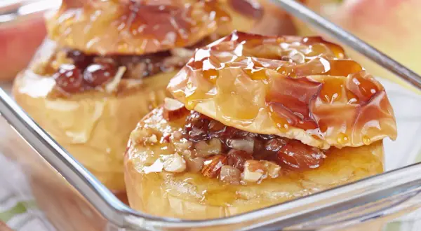 Deux pommes au four dorées, garnies de noix et de raisins secs, nappées d'un sirop brillant. Un délice gourmand.
