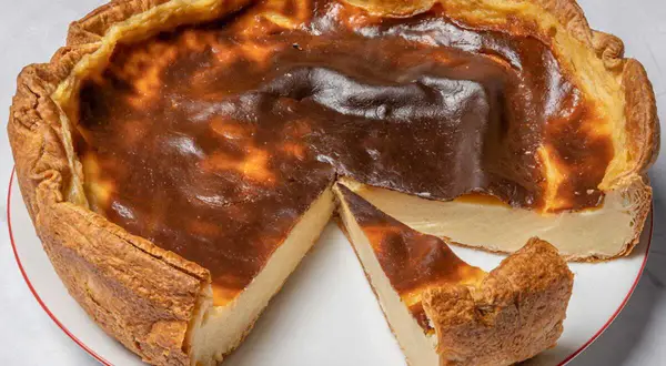 Un flan pâtissier doré, avec une croûte croustillante et une garniture crémeuse, une part coupée révèle sa texture onctueuse.