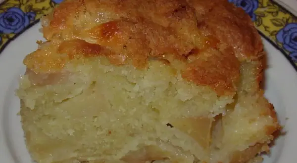 Une part de moelleux aux pommes, avec sa croûte dorée et sa mie tendre, prête à être dégustée.