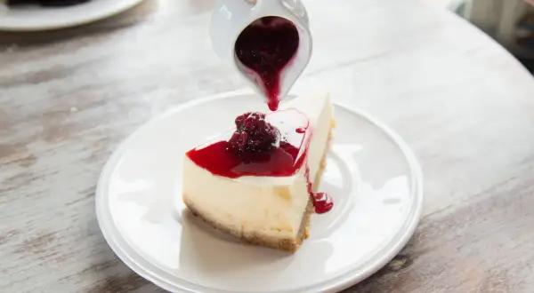 Un délicieux cheesecake garni de coulis de fruits rouges, un dessert rapide sans cuisson parfait pour se régaler.