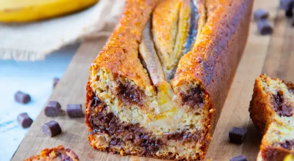 Un délicieux banana bread aux pépites de chocolat, garni de bananes entières sur le dessus.