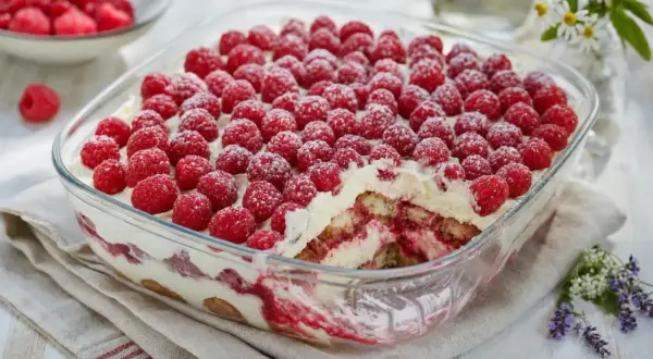 Un délicieux tiramisu framboise, généreusement garni de fruits rouges frais et saupoudré de sucre glace.