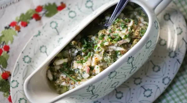 Sauce ravigote fraîche et acidulée, garnie de ciboulette ciselée, dans un saucier décoré.