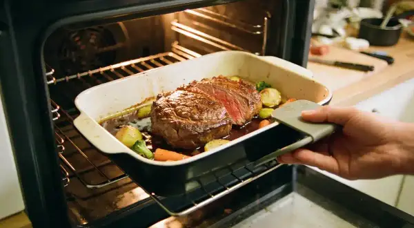 Un rosbeef juteux avec des légumes rôtis sort du four. Le temps de cuisson au four est presque terminé, prêt à être dégusté.