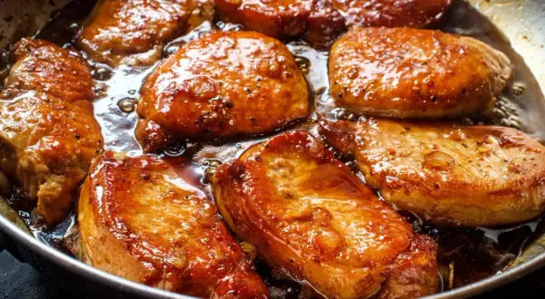 Filet mignon en train de dorer dans une poêle, baignant dans une sauce caramélisée. La marinade leur donne une belle couleur dorée et appétissante.