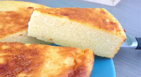 Un gâteau arabe semoule extra fine, doré et moelleux, servi sur une assiette bleue. Sa texture légère promet un délice.