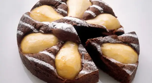 Gâteau poire chocolat, un délice moelleux parsemé de sucre glace, avec des poires fondantes incrustées dans la pâte.