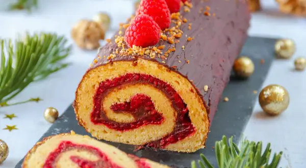 Bûche au chocolat et framboises, parfaite pour une recette de fête. Décorée de fruits rouges et de noisettes concassées.