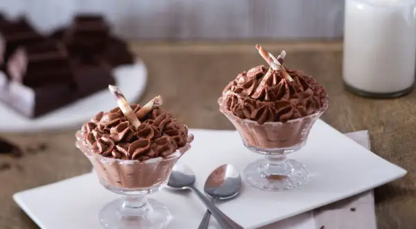 Deux coupes de mousse au chocolat sans oeuf, garnies de bâtonnets de chocolat blanc et brun.