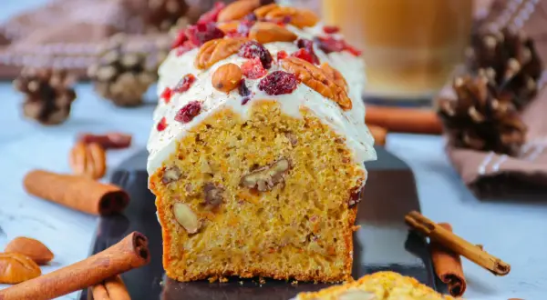 Un délicieux carotte cake glacé, garni de noix et de canneberges, prêt à être dégusté. Une recette parfaite pour le goûter.