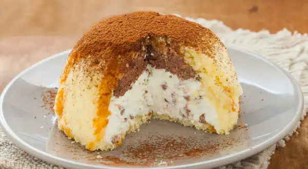 Gâteau glacé en forme de dôme, garni de crème et de chocolat, saupoudré de cacao. Parfait pour une recette génoise.