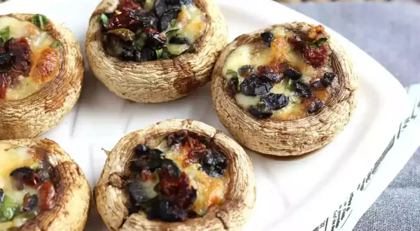 Champignons farcis au four, garniture aux olives noires et tomates séchées, fromage fondant. Une recette simple et savoureuse.