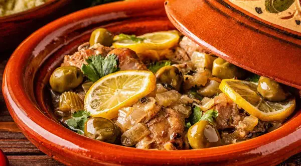 Un plat de tajine aux citrons confits, olives vertes et herbes fraîches, prêt à être dégusté.