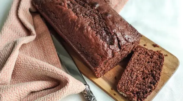 Un délicieux gâteau yaourt chocolat, moelleux et gourmand, prêt à être dégusté. Une tranche est déjà coupée.