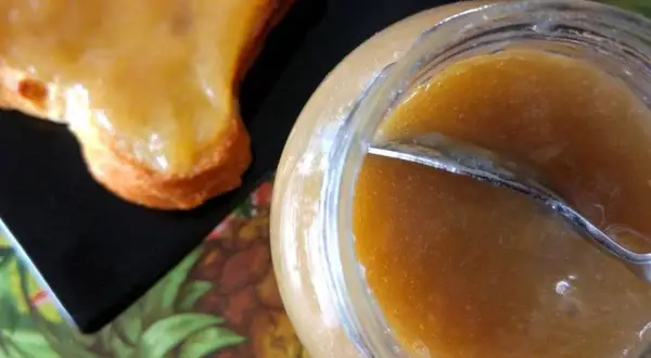 Un pot de confiture rhubarbe banane et une tartine généreusement garnie. Une gourmandise maison prête à être dégustée.