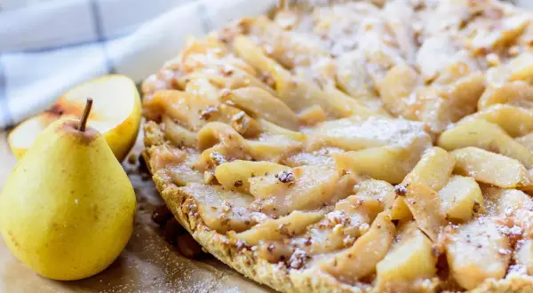 Délicieuse tarte aux poires, garnie de fruits frais et saupoudrée de sucre glace. Un délice pour les yeux et les papilles.