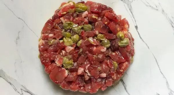 Un délicieux tartare de bœuf gastronomique, préparé avec soin et garni de câpres, prêt à être dégusté.
