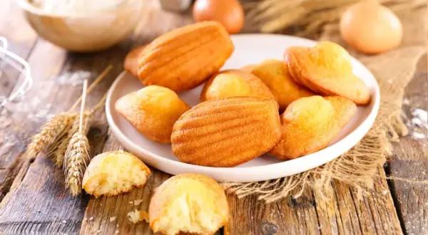 Assiette de madeleines dorées, prêtes à être dégustées. Une recette simple pour un goûter parfait.