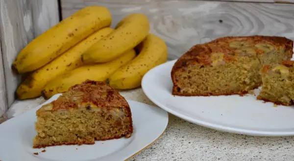 Tranches de gâteau yaourt banane moelleux, avec des bananes fraîches en arrière-plan. Un délice simple et réconfortant.