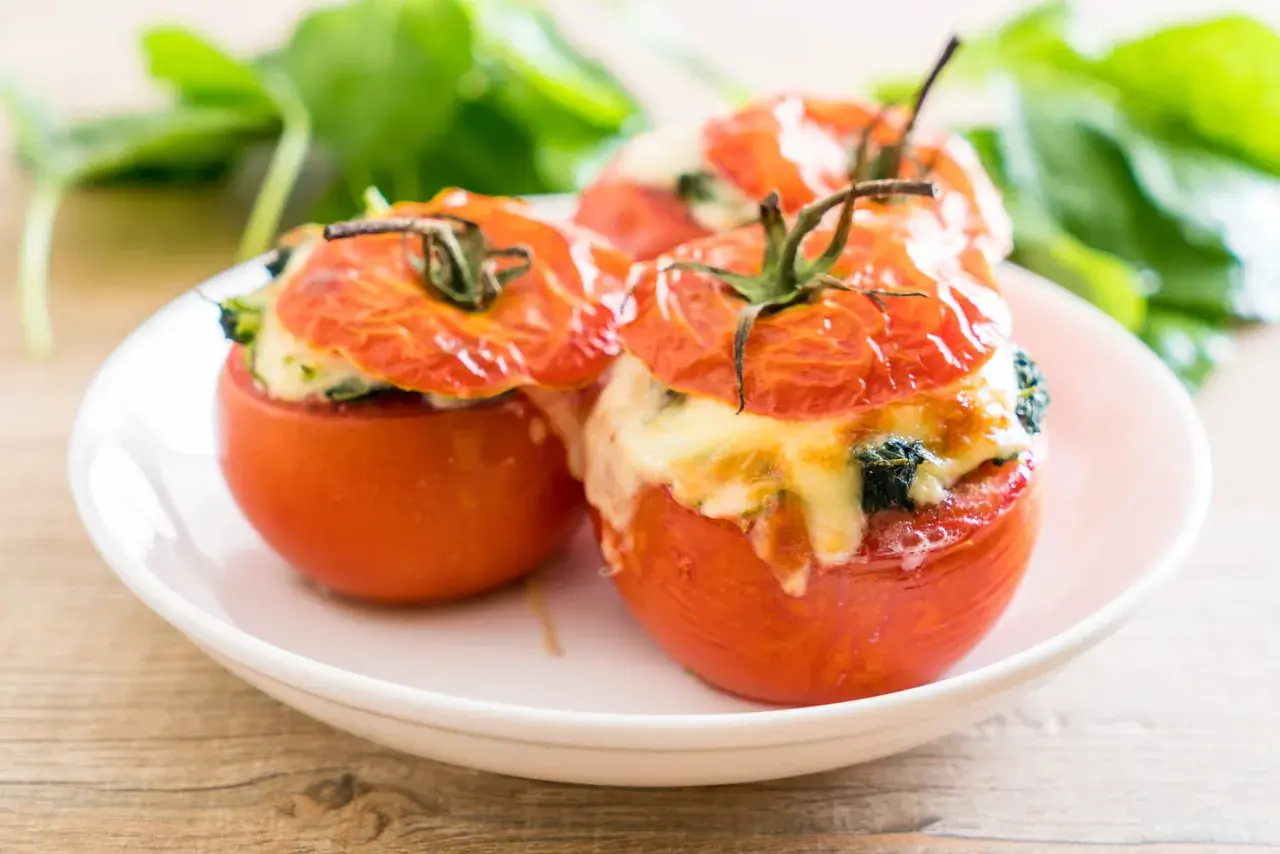 Trois tomates farcies au fromage et aux herbes, prêtes à être dégustées. Une recette simple et savoureuse.