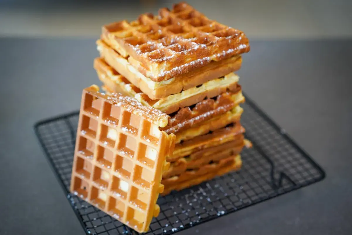 Pile de gaufres dorées et croustillantes, saupoudrées de sucre glace. La recette parfaite pour un petit-déjeuner gourmand.