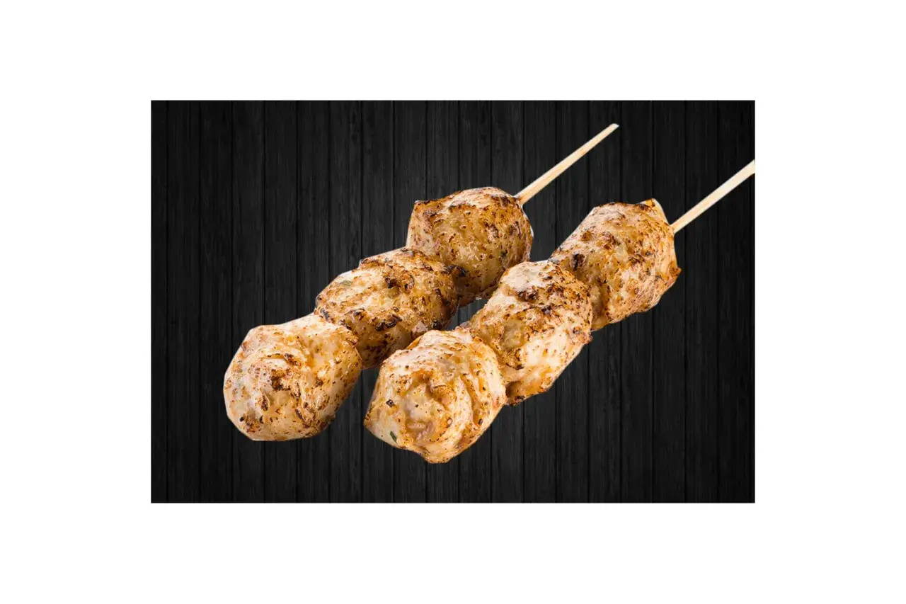 Deux brochettes de boulettes de poulet yakitori grillées, sur fond de bois sombre.