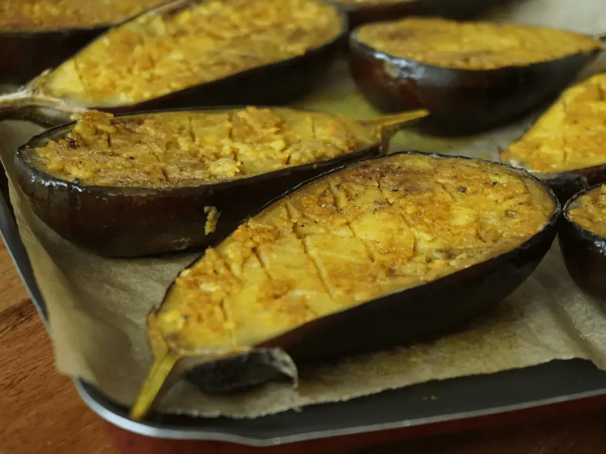 Aubergines au four, coupées en deux et garnies d'une préparation dorée, prêtes à être dégustées.