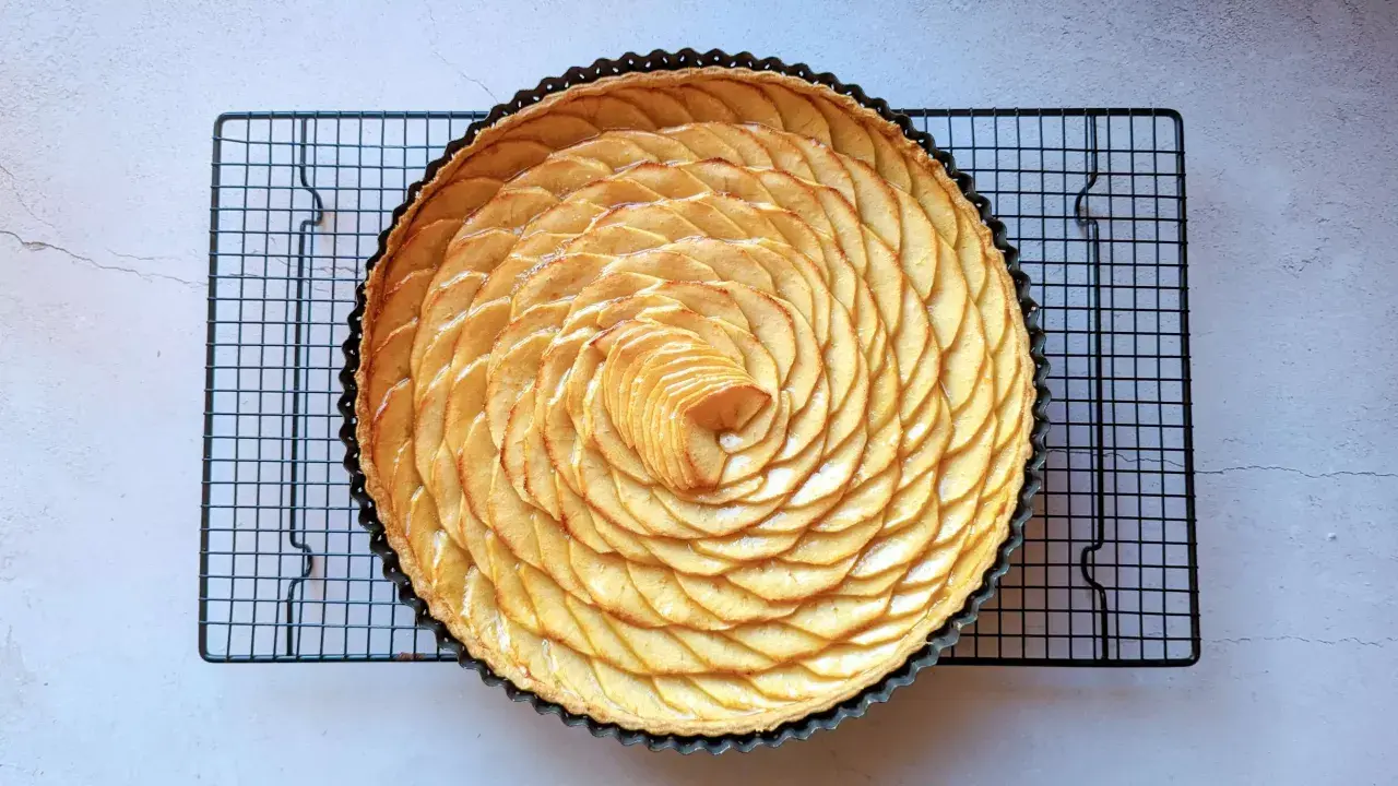 Tarte aux pommes recette de maman, magnifiquement décorée de fines tranches de pommes disposées en spirale sur une pâte dorée.