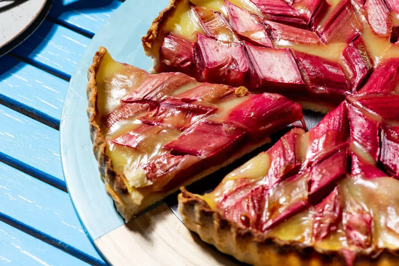 Tarte à la rhubarbe sur pâte feuilletée, garnie de fruits rouges et d'une crème dorée. Un délice estival.