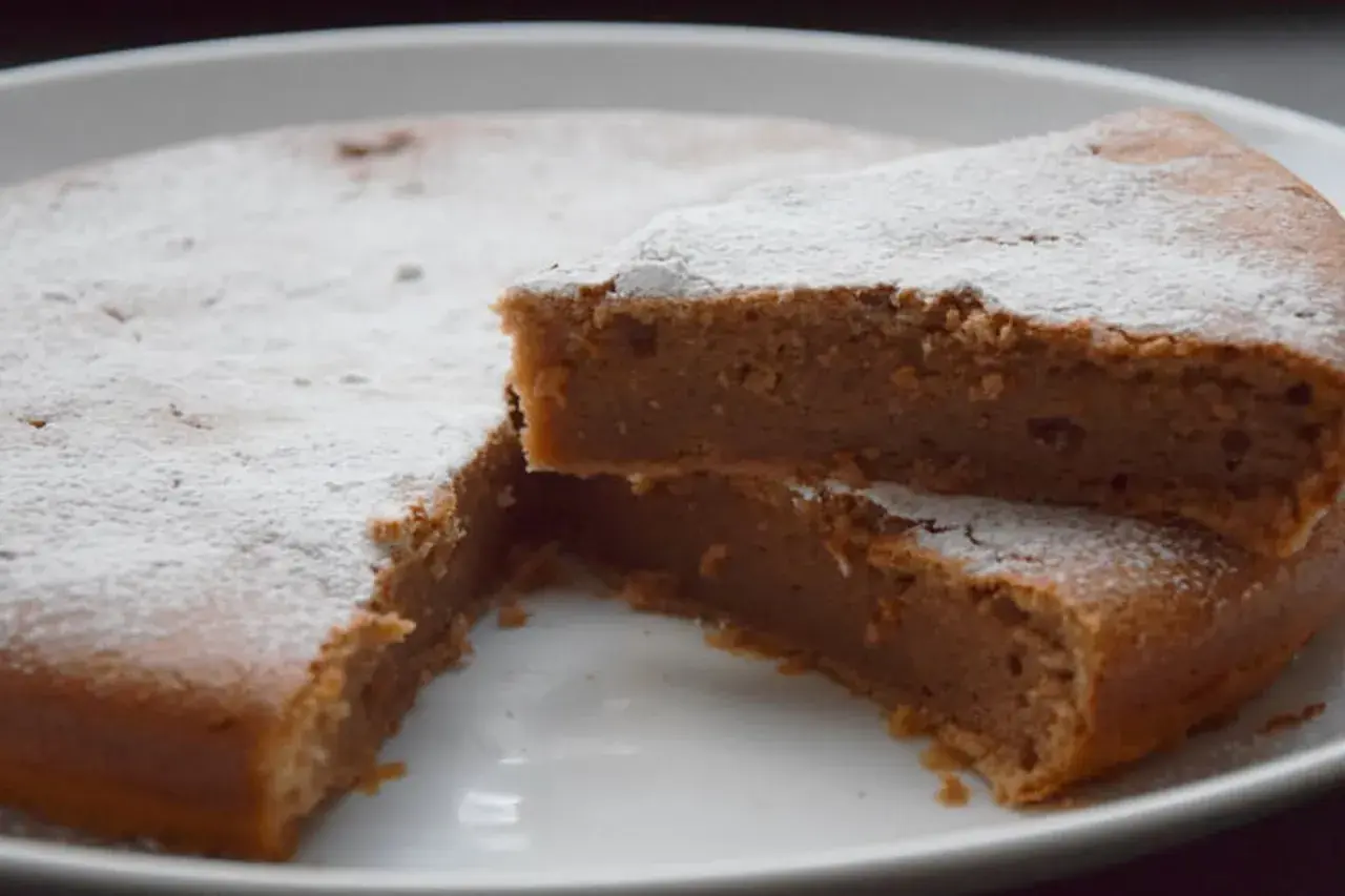 Un délicieux gâteau à la crème de marron, saupoudré de sucre glace, avec une part coupée pour révéler sa texture moelleuse.