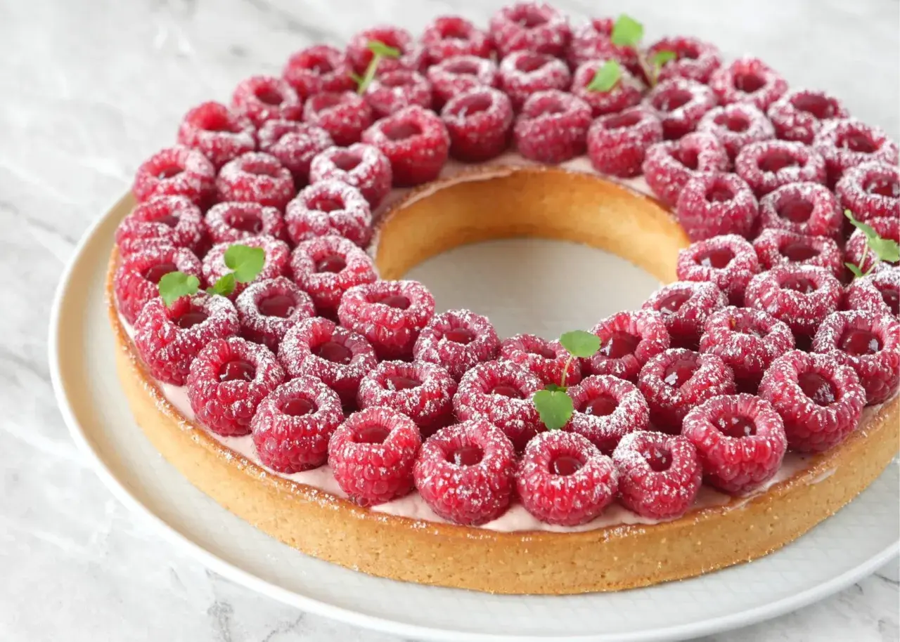 Une magnifique tarte à la framboise facile, garnie de fruits rouges frais et saupoudrée de sucre glace. Parfaite pour un dessert gourmand.