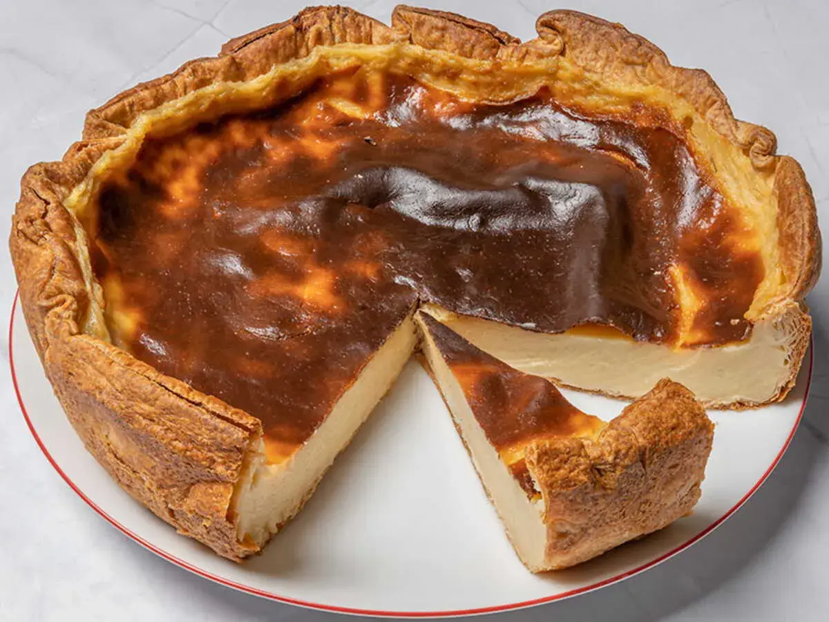 Un flan pâtissier doré, avec une croûte croustillante et une garniture crémeuse, une part coupée révèle sa texture onctueuse.