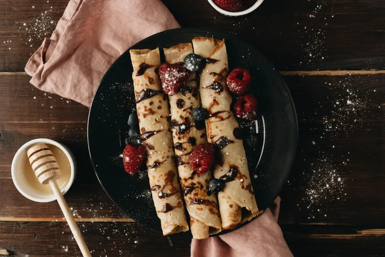 Crêpes roulées garnies de fruits rouges et de chocolat, prêtes à être dégustées. Une recette simple et gourmande pour le petit-déjeuner ou le goûter.