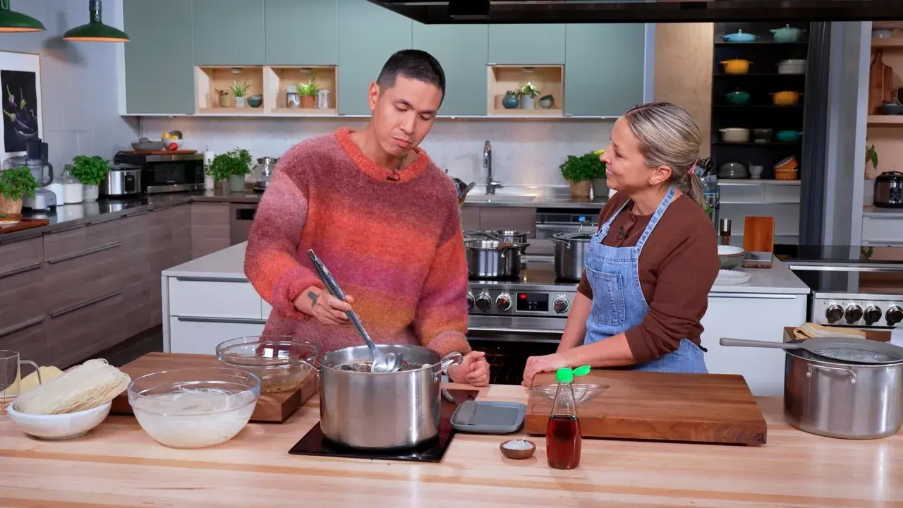 Un homme et une femme préparent un plat dans une cuisine. Le bouillon de poulet mijote dans une grande casserole.