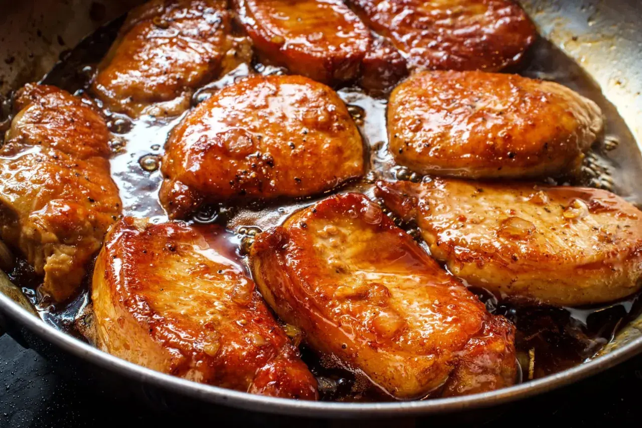 Filet mignon en train de dorer dans une poêle, baignant dans une sauce caramélisée. La marinade leur donne une belle couleur dorée et appétissante.
