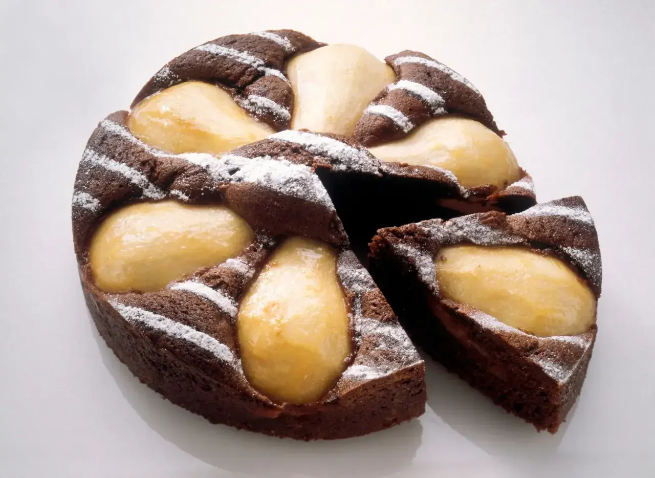 Gâteau poire chocolat, un délice moelleux parsemé de sucre glace, avec des poires fondantes incrustées dans la pâte.