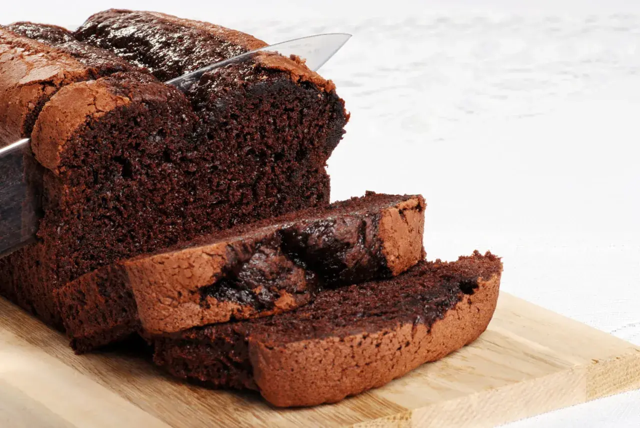 Un délicieux gâteau au chocolat sans beurre, coupé en tranches sur une planche en bois. Sa texture moelleuse et son goût intense invitent à la gourmandise.