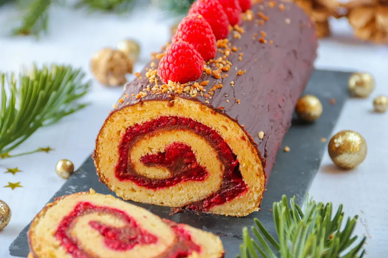 Bûche au chocolat et framboises, parfaite pour une recette de fête. Décorée de fruits rouges et de noisettes concassées.