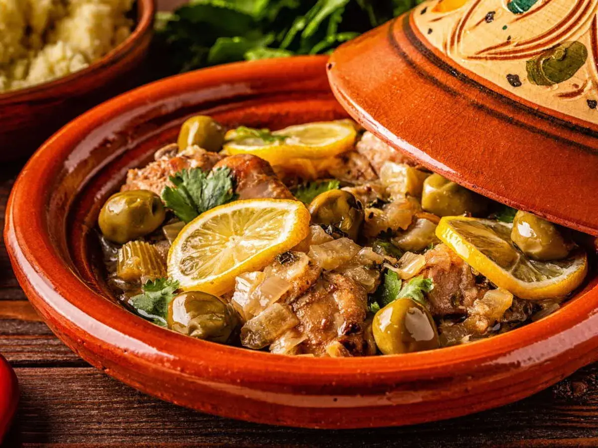 Un plat de tajine aux citrons confits, olives vertes et herbes fraîches, prêt à être dégusté.