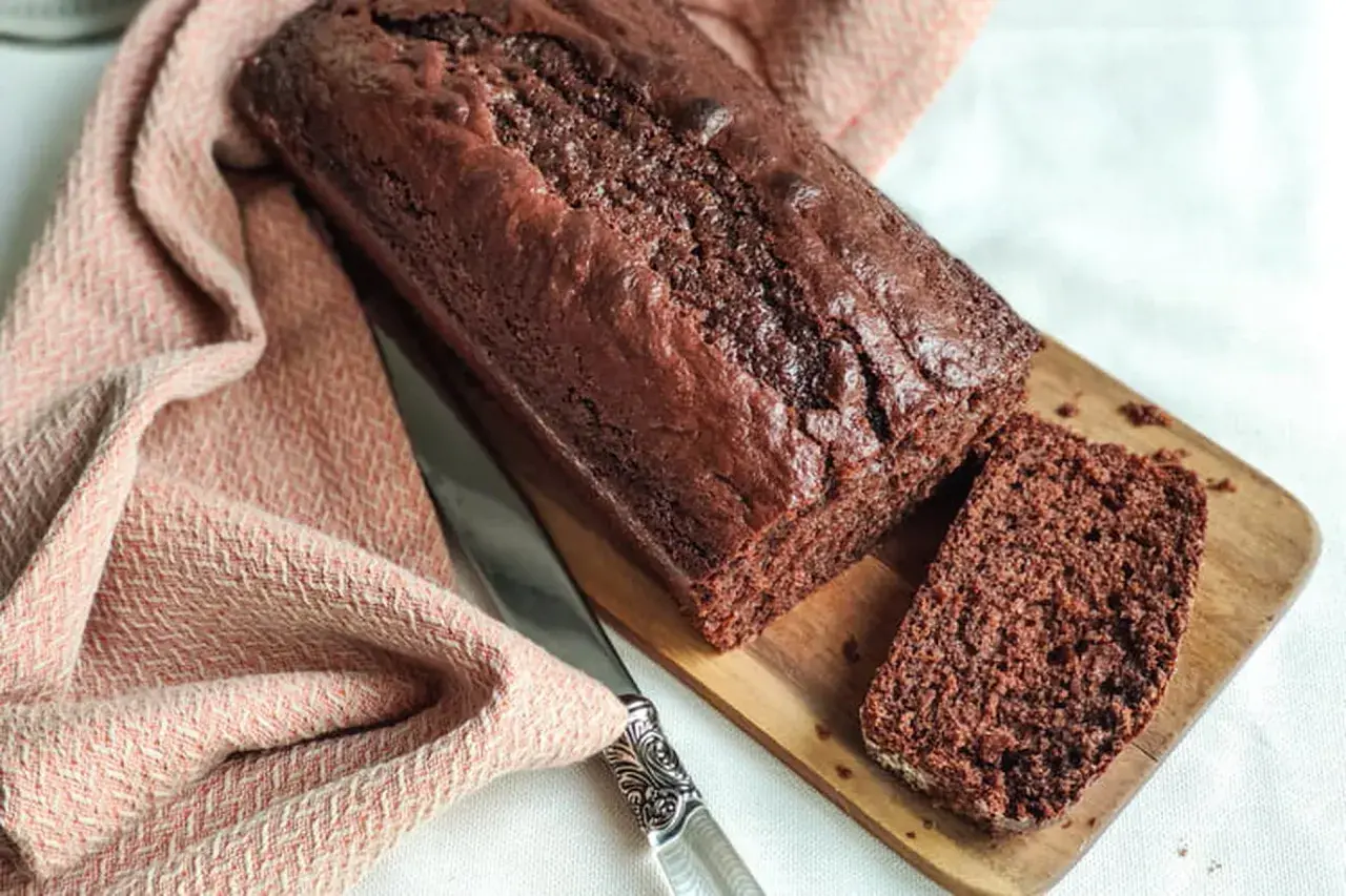 Un délicieux gâteau yaourt chocolat, moelleux et gourmand, prêt à être dégusté. Une tranche est déjà coupée.
