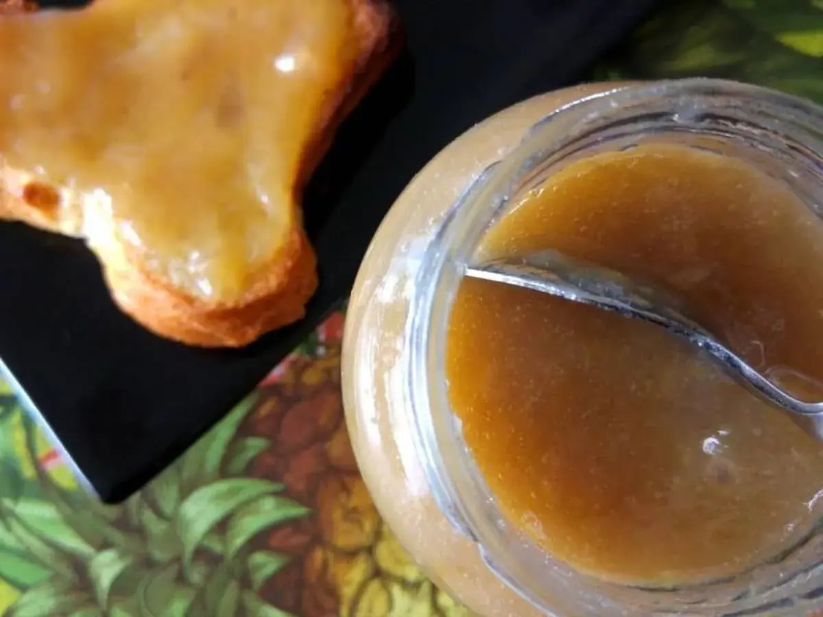 Un pot de confiture rhubarbe banane et une tartine généreusement garnie. Une gourmandise maison prête à être dégustée.