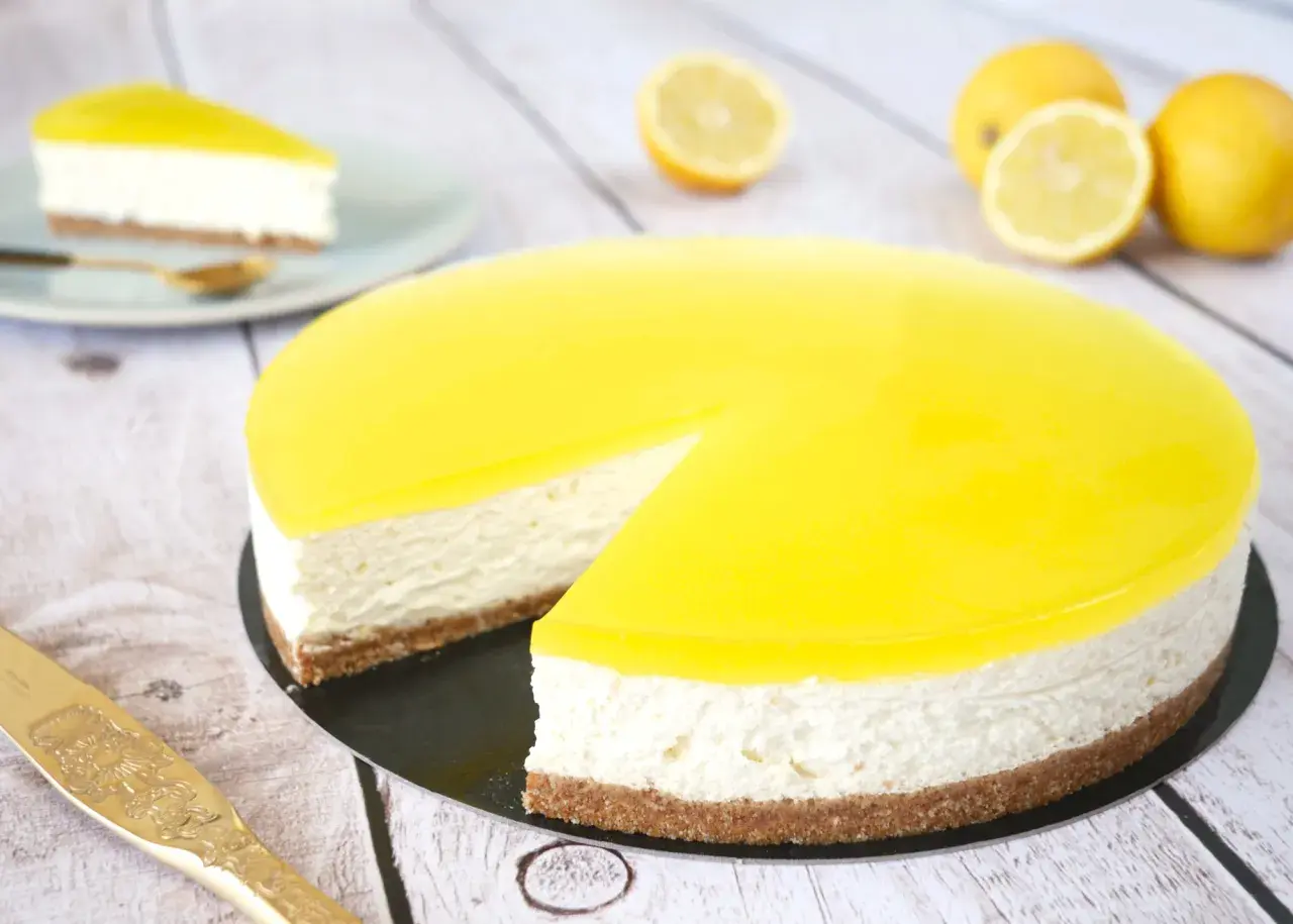 Cheesecake citron mascarpone, un délice jaune vif sur fond de bois. Une part est déjà servie.
