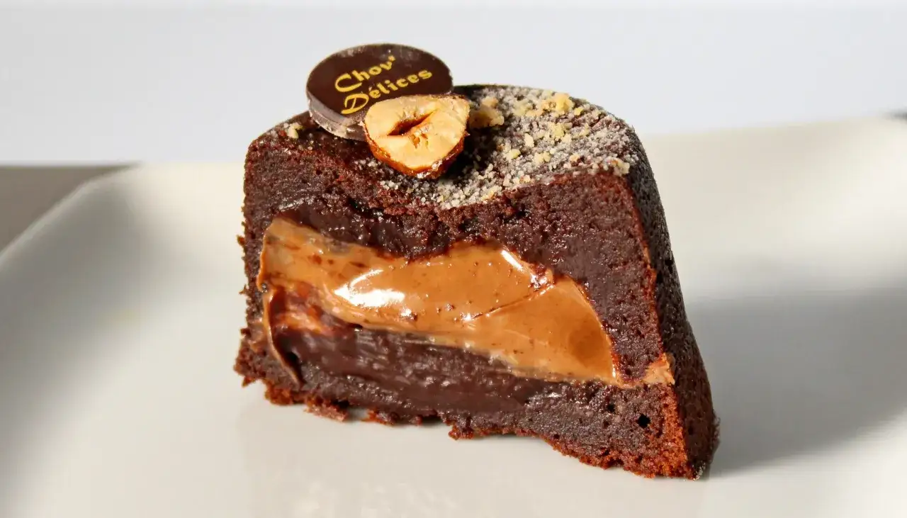 Tranche de gâteau chocolat Pierre Hermé, garnie d'une ganache onctueuse et d'une noisette croquante.