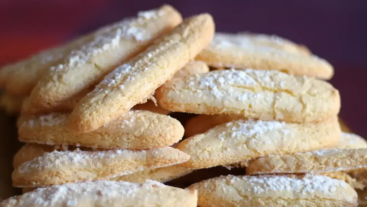 Gros plan sur une pile de biscuits cuillère saupoudrés de sucre glace, parfaits pour une recette Cyril Lignac.