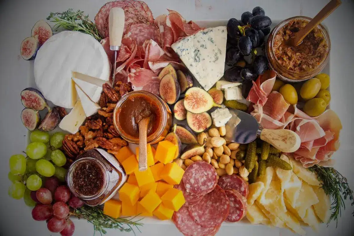 Plateau gourmand : une planche charcuterie fromage avec fruits, noix et confitures.