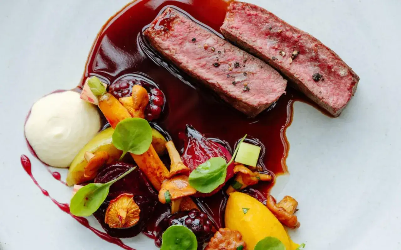 Tranches de bœuf juteuses nappées d'une sauce viande rouge profonde, accompagnées de légumes racines colorés et d'une purée onctueuse.