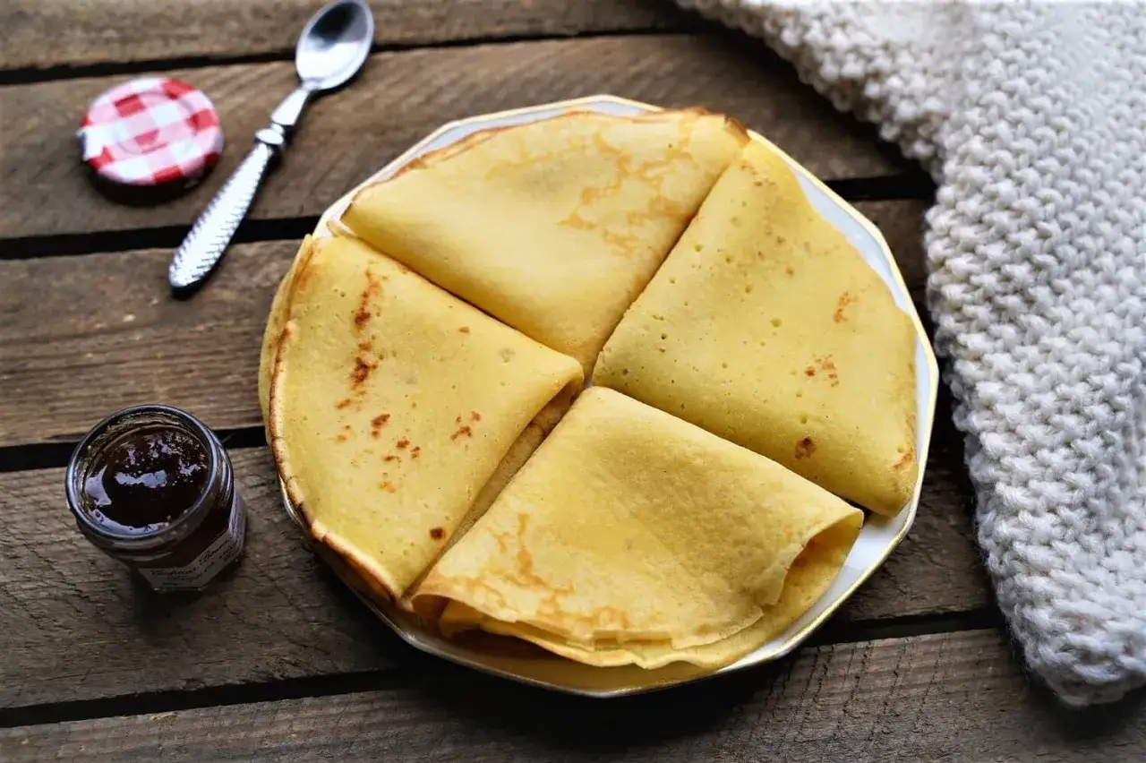 Cr&ecirc;pes dor&eacute;es sur une assiette, accompagn&eacute;es d'une petite confiture. Une recette p&acirc;te &agrave; cr&ecirc;pe facile sans repos pour un plaisir imm&eacute;diat.