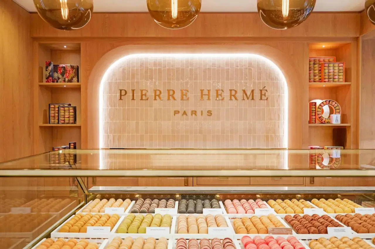 Vitrine de macarons colorés chez Pierre Hermé Paris. Une invitation à découvrir la recette parfaite.