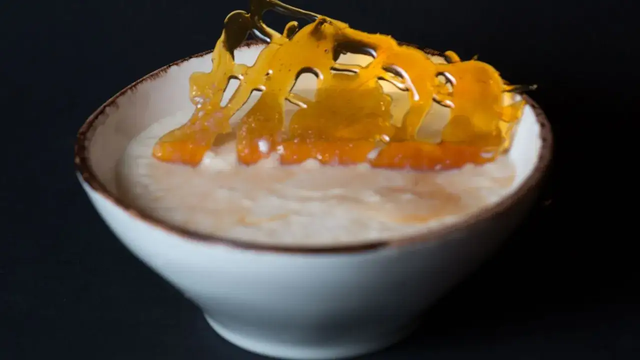 Un bol de riz au lait crémeux, garni d'une décoration en caramel ambré et de morceaux d'orange confite.