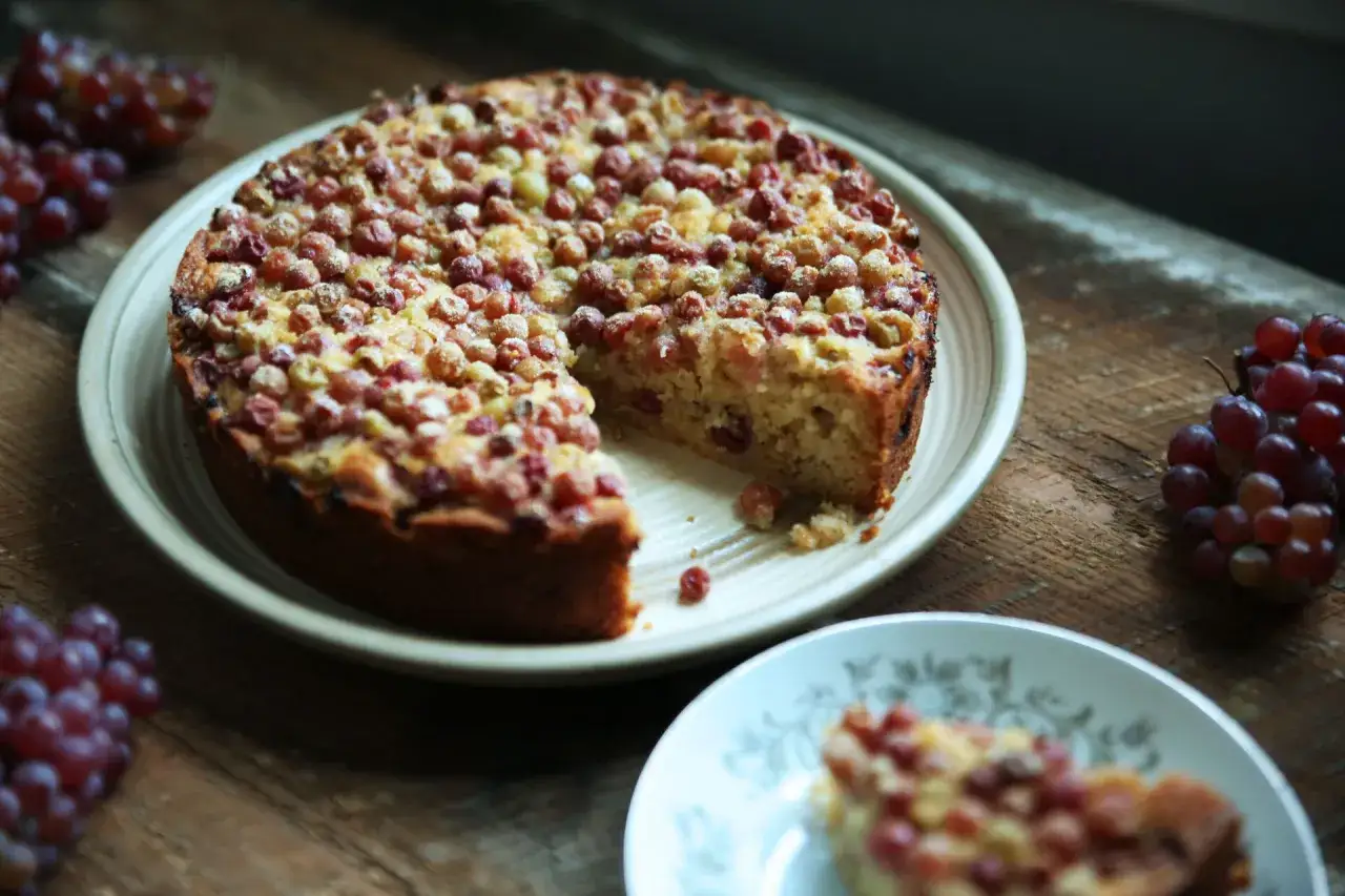 Gâteau aux raisins secs moelleux, garni de fruits rouges. Une tranche est servie sur une assiette.